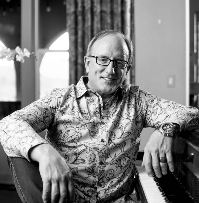 Dr. Bonaldi sitting casually at his piano bench